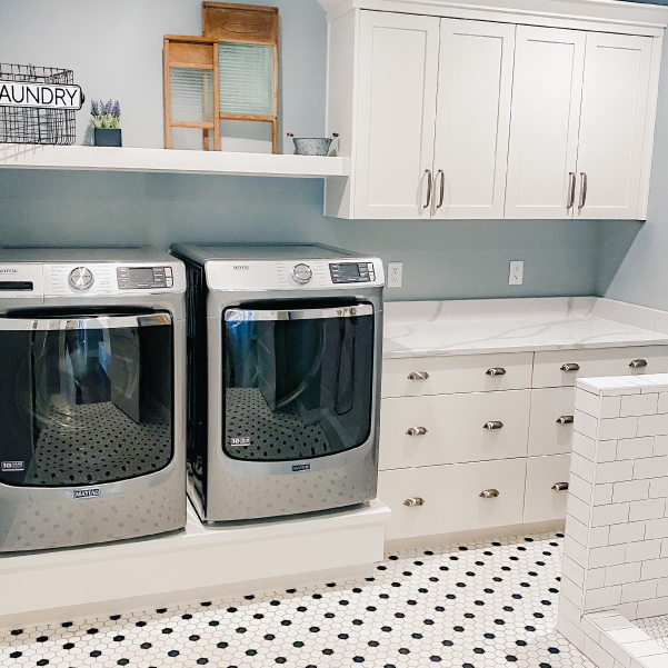 A white farmhouse laundry room with a stainless steel washer and dryer