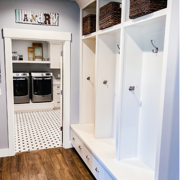 Hallway cabinets with baskets and hooks outside the laundry room door of a modern farmhouse