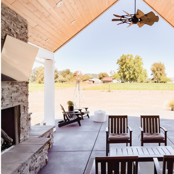 Outdoor covered seating area with fireplace and overhead fan