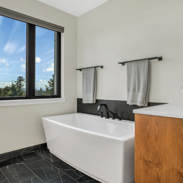 Striking white-and-black bathroom featuring a full tub in a modern home built by Mike Riddle Construction