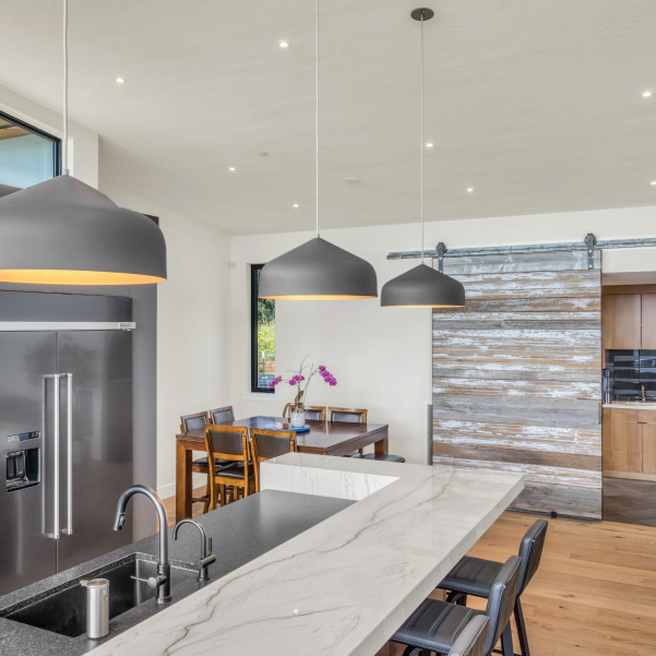 Sliding barn door and marble sit-up kitchen island in a built by Mike Riddle Construction