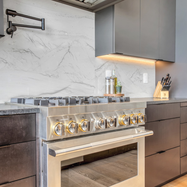 A stainless steel stove in a kitchen with a marble backsplash and mixed color countertops built by Mike Riddle Construction