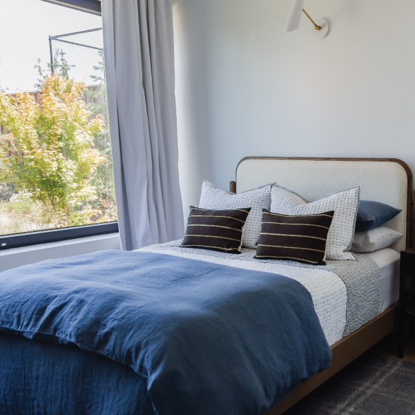 Full-sized bed dressed in bedding for a masculine organic modern style in Lagom built by Mike Riddle Construction