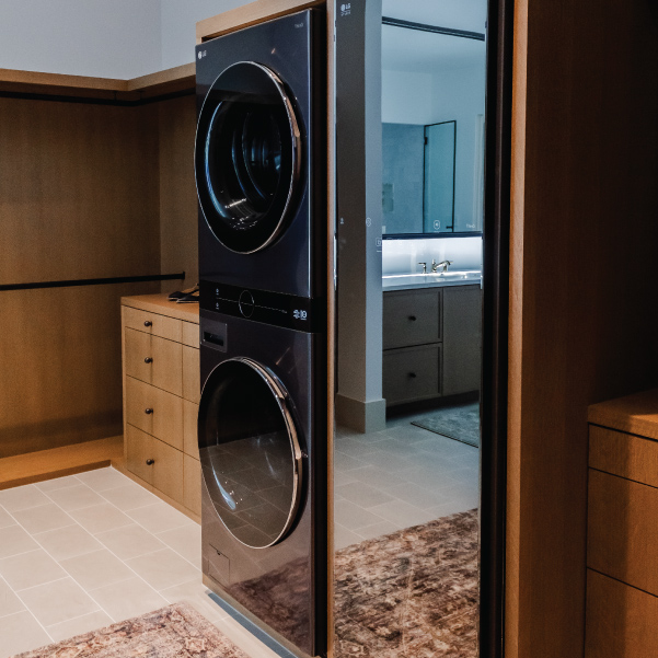 Modern washer and dryer in a walk-in closet of Lagom built by Mike Riddle Construction