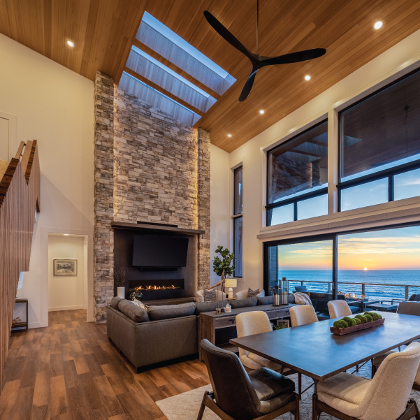 Sunset view from the kitchen into the dining and living area of a custom Oregon Coast home built by Mike Riddle Construction