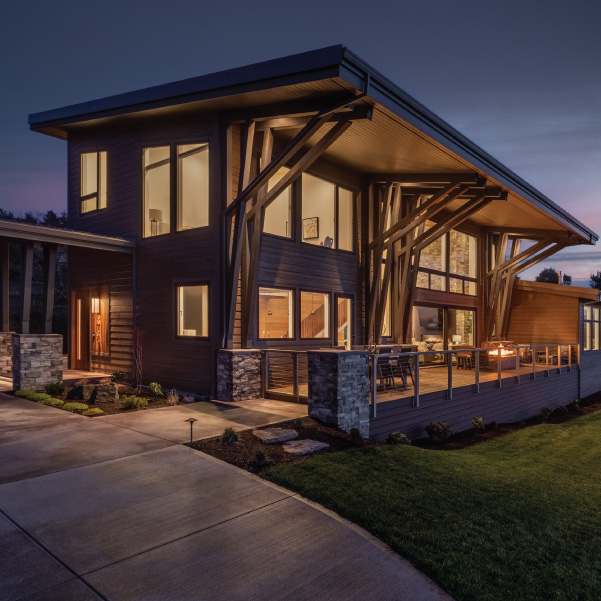 Nighttime view of a interiorly lit modern coastal home built by Mike Riddle Construction