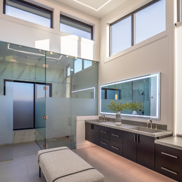 White bathroom with high ceiling and windows in a modern home by Mike Riddle Construction