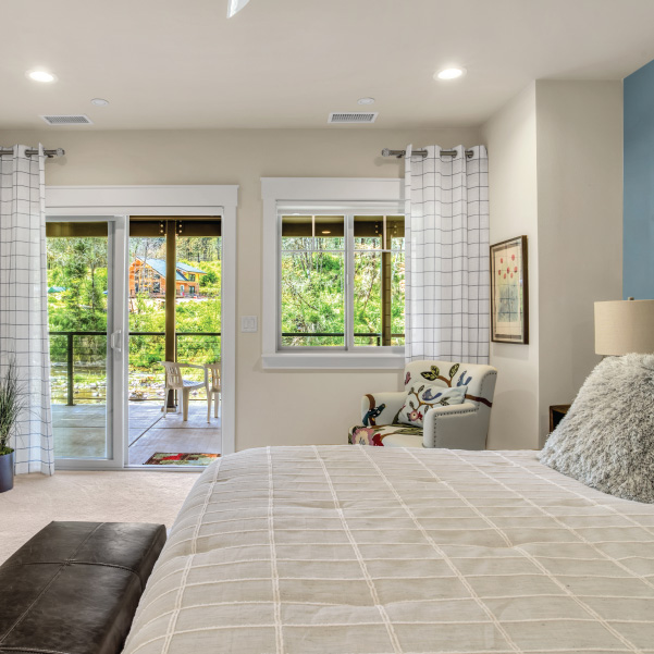 White bedroom with a sliding door leading out to patio area