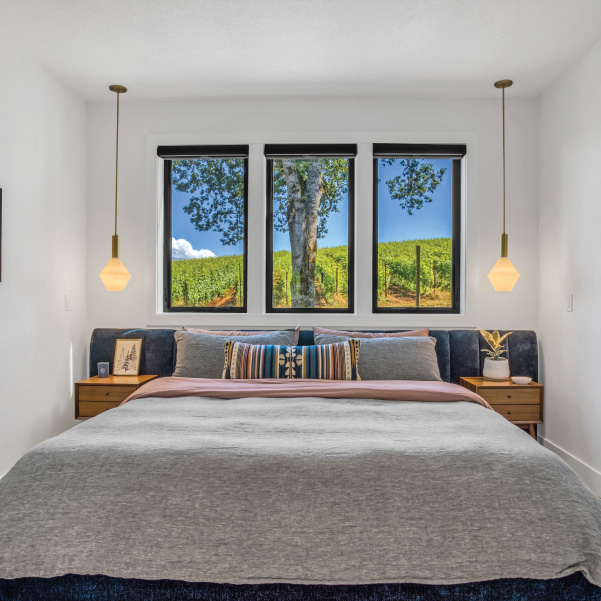 Master bedroom with three vertical windows for a vineyard view for a wine country home built by Mike Riddle Construction