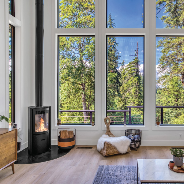 Freestanding wood stove next to tall vertical windows in a custom home built by Mike Riddle Construction