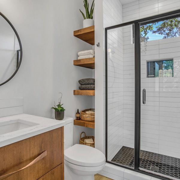 Tiled walk-in closet with wood shelves holding plants and towels in a custom home built by Mike Riddle Construction