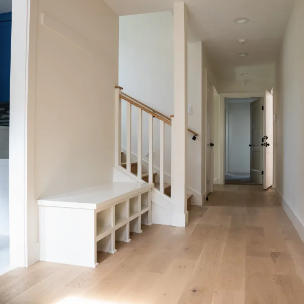 Look down a hallway with a shoe cubby bench at the base of a stairway