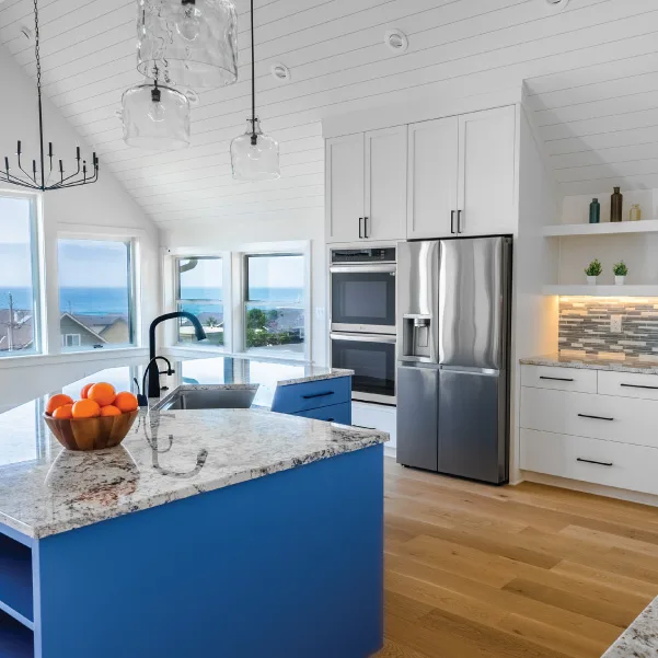 Large kitchen island with blue cabinets and windows with an ocean view