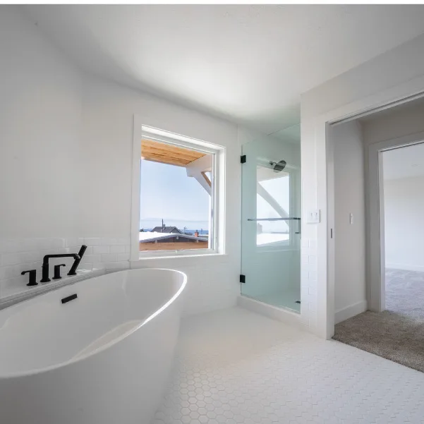 White soaking tub with walk-in shower with large square window with an ocean view